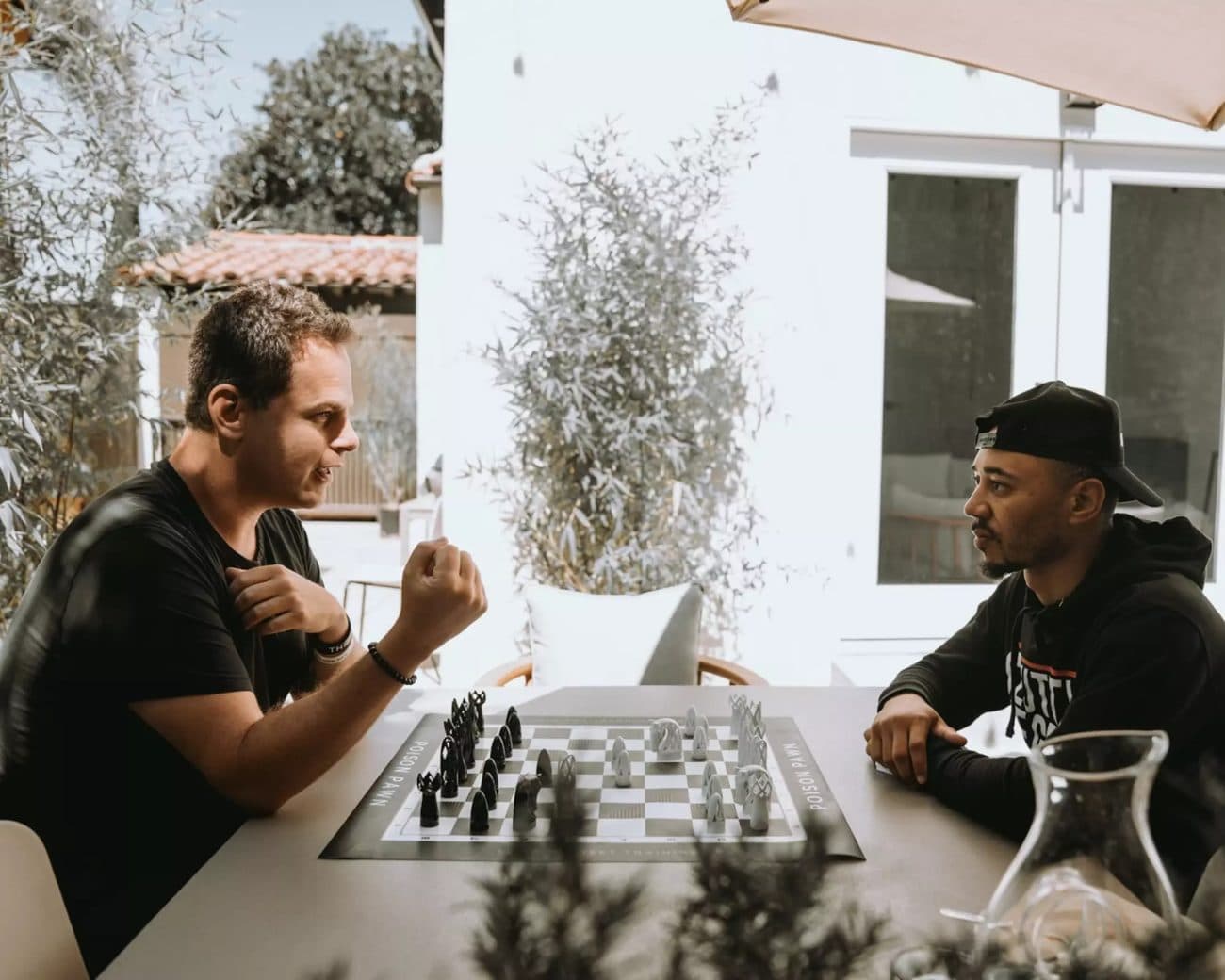 Seth Makowsky playing chess with Mookie Betts on an outdoor patio.