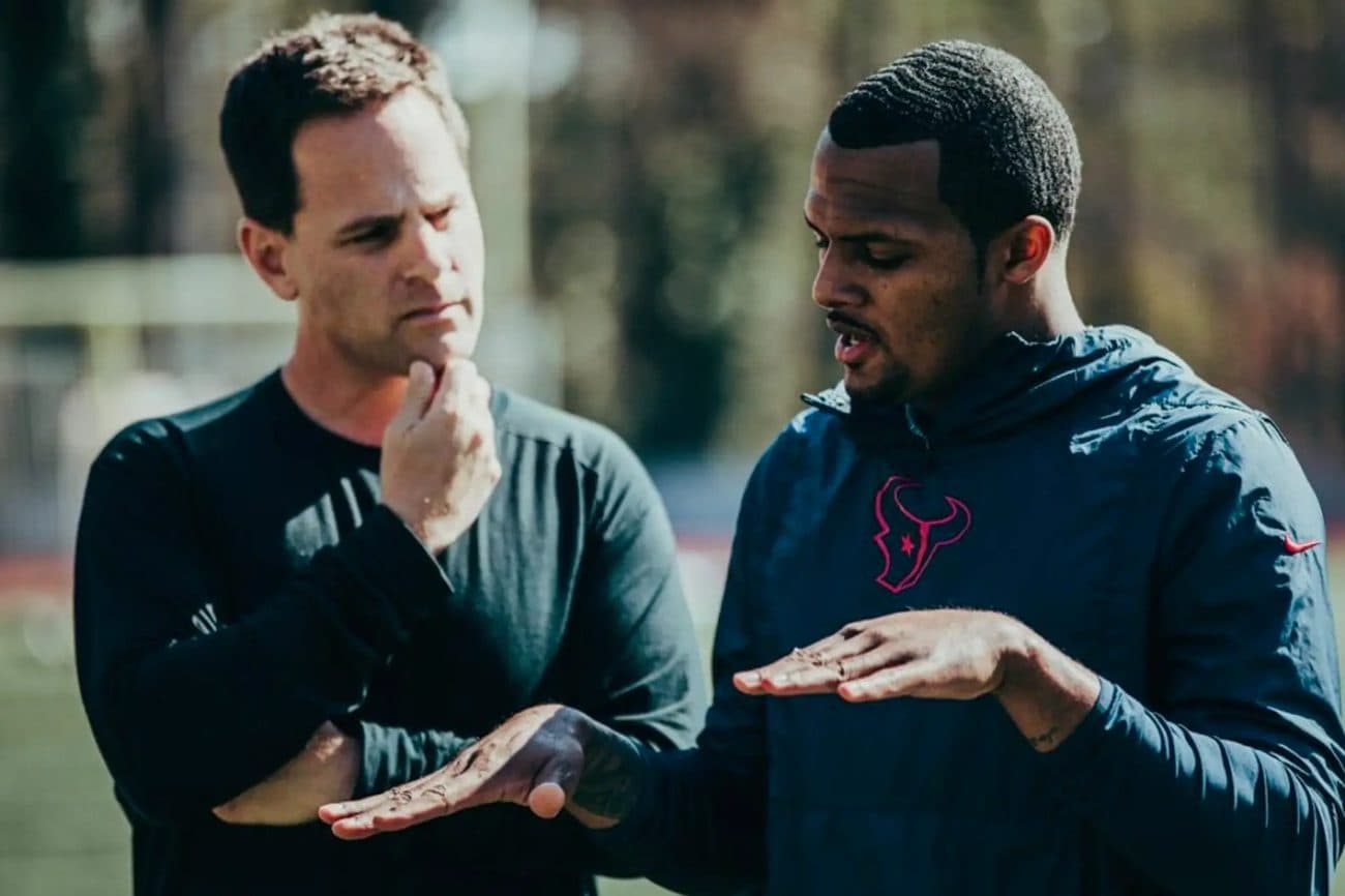 Seth Makowsky and Deshaun Watson talk through a drill on the field, gesturing with their hands.