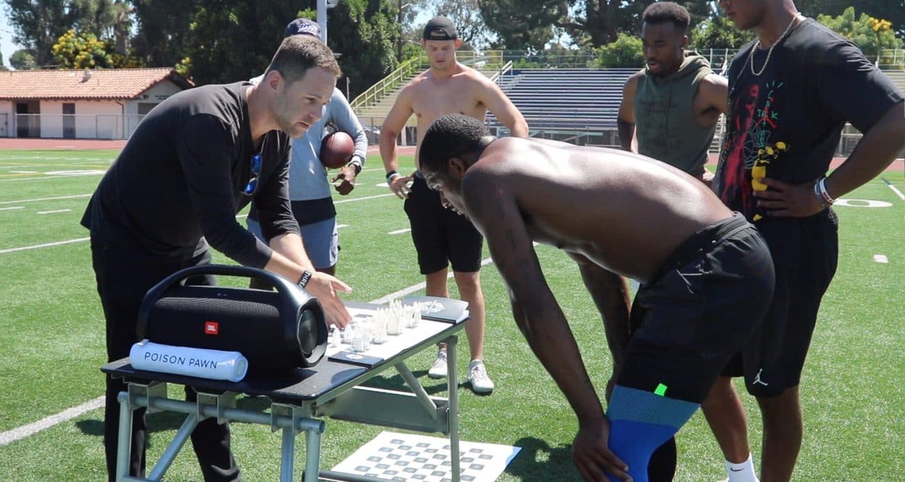 Makowsky leads quarterbacks through an on-field chess drill with a Poison Pawn board.